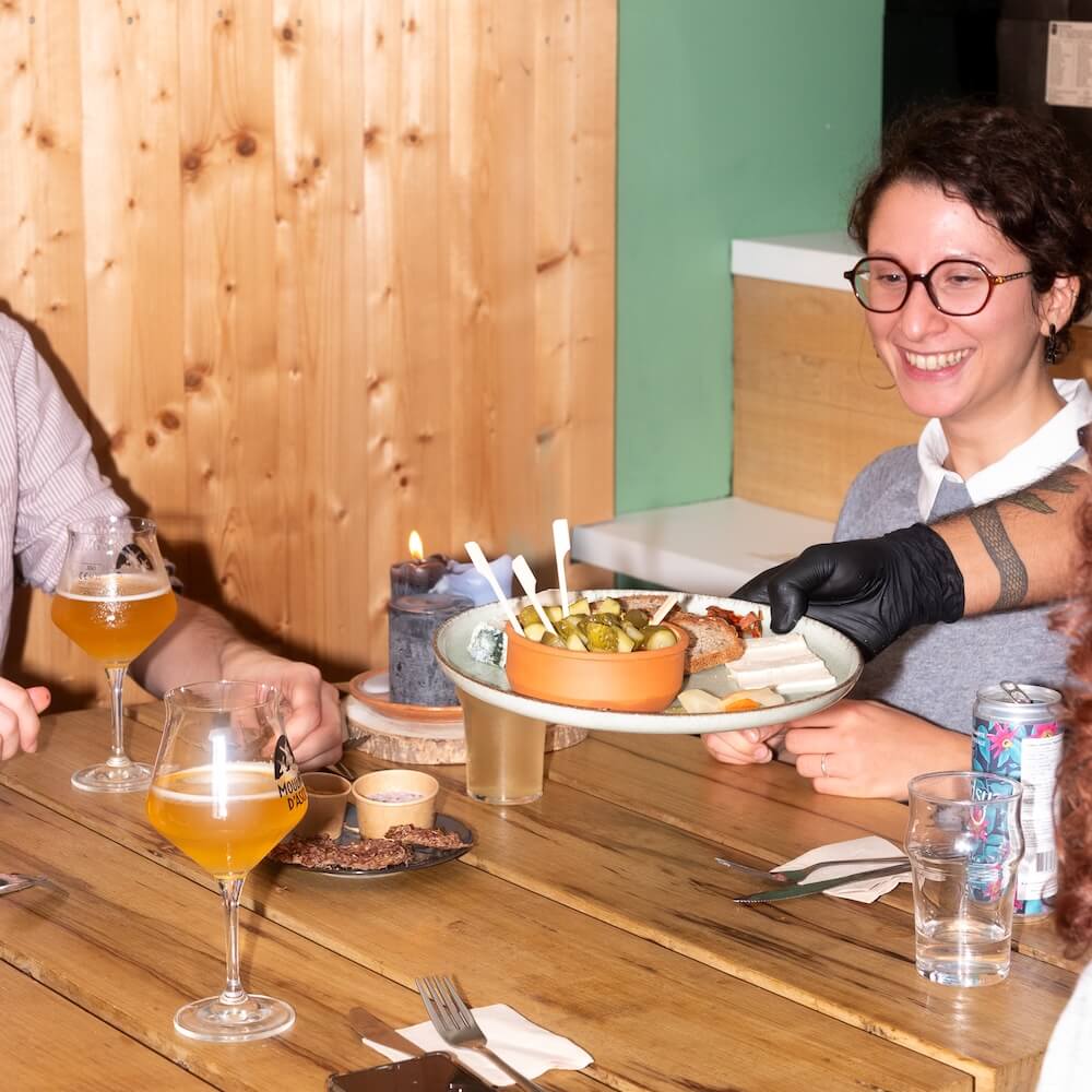 flash photography of a woman sitting at a restaurant table and waiter serving her food